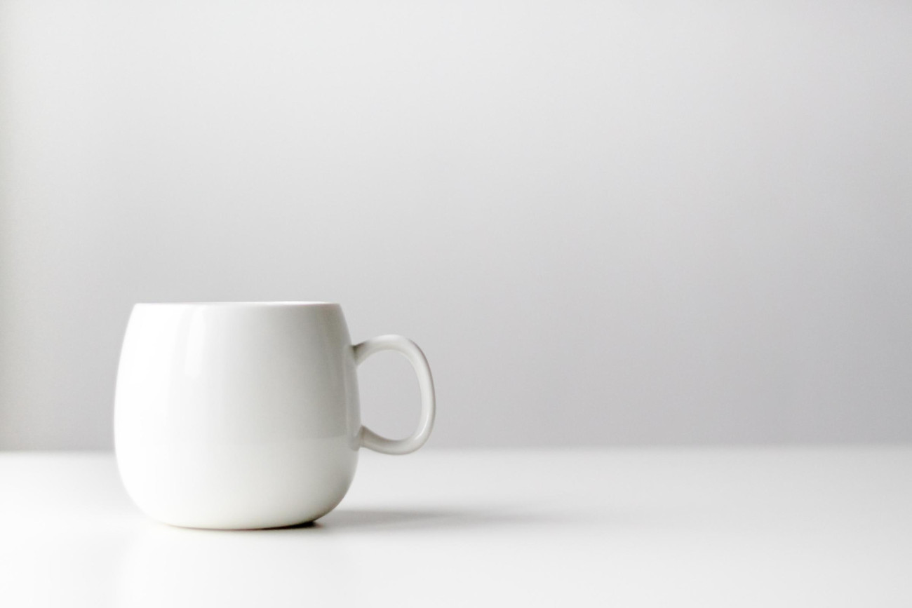 Eine weiße Tasse vor einem einfachen, weißen Hintergrund