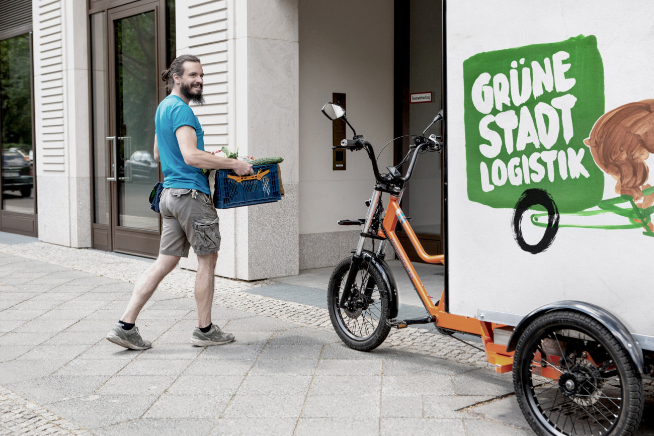 Lieferant und Cargobike mit der Aufschrift "Grüne Stadtlogistik"
