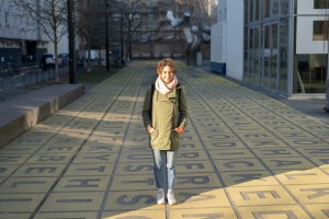 Eine Frau steht auf einem Platz und lächelt in die Kamera