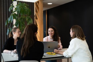 Celina Müller und drei Kolleginnen sitzen am Tisch im Büro mit dem Laptop