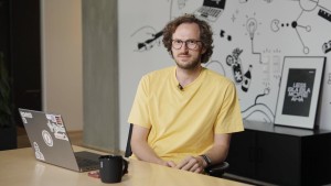 Ein Mann sitzt an einem Schreibtisch mit einem Laptop und einer Tasse